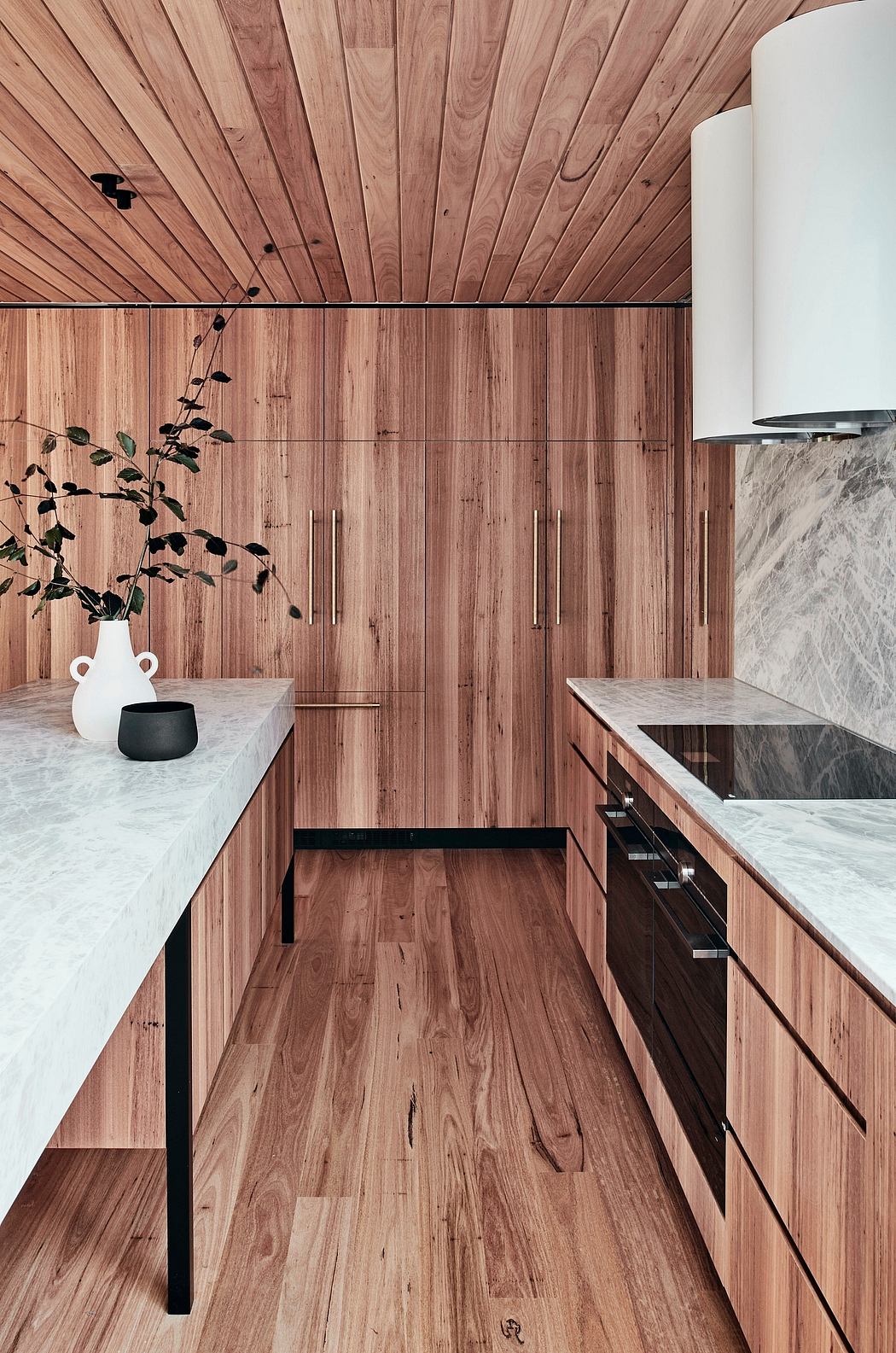 A modern kitchen with sleek wooden cabinets, marble countertops, and a striking wooden ceiling.