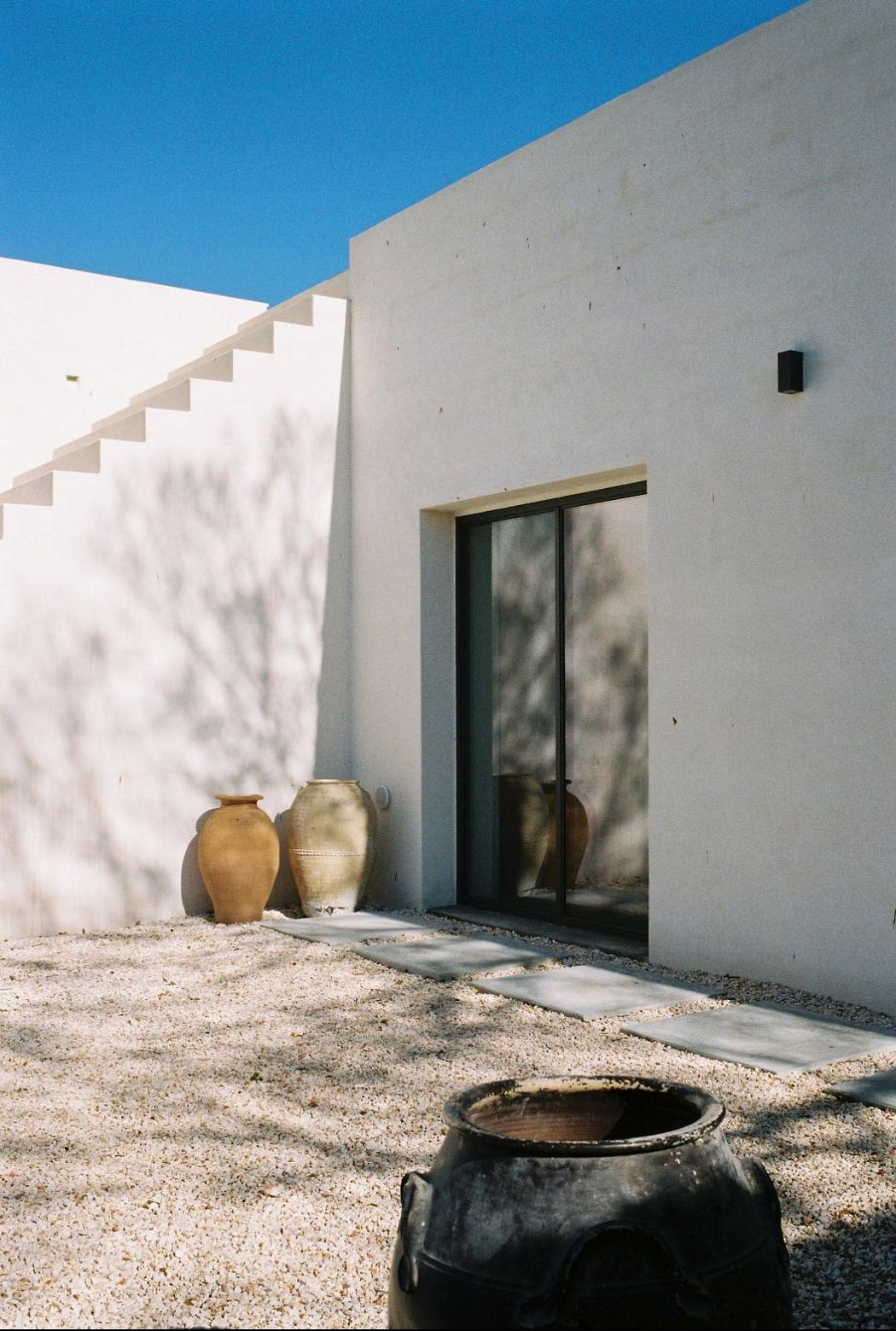 Minimalist architecture featuring concrete walls, potted plants, and a tranquil courtyard.
