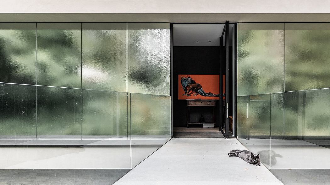 Modern glass exterior with red accent door revealing a cat lounging inside.