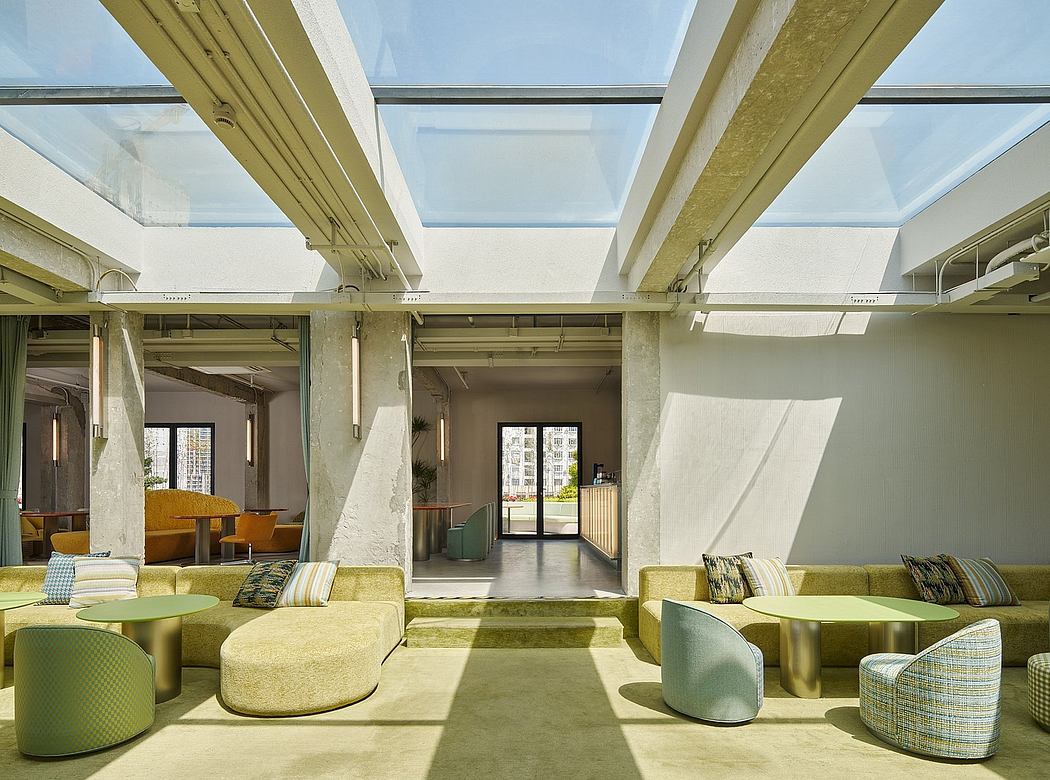 Spacious modern interior with skylights, concrete beams, and vibrant upholstered furniture.