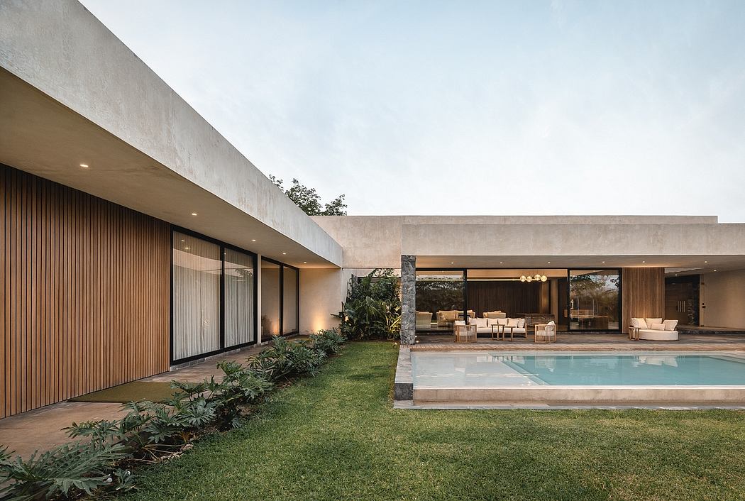 Sleek, modern architecture with expansive glass walls, pool, and lush landscaping.
