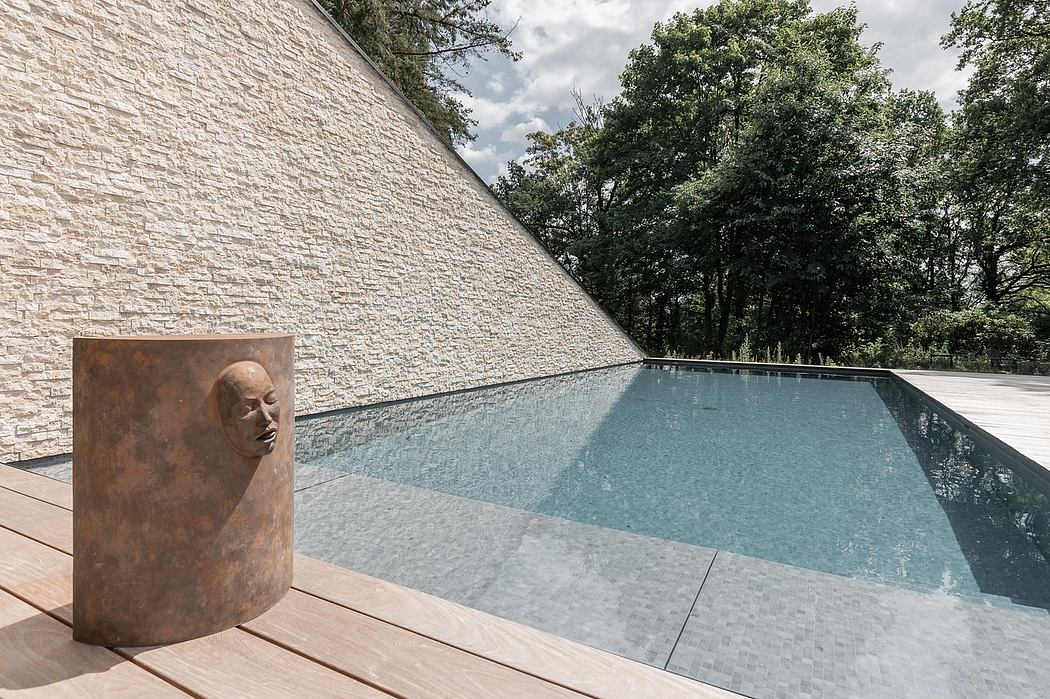 Serene outdoor pool surrounded by stone walls and lush greenery, with a sculptural element.