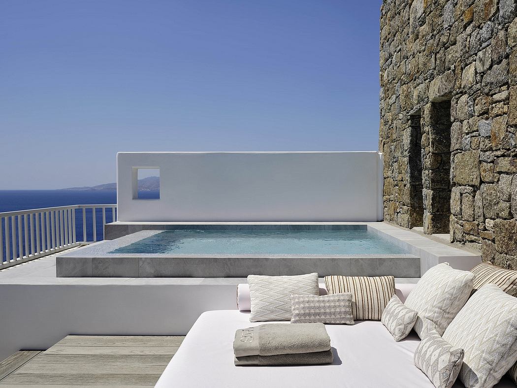 Sleek, modern pool terrace with neutral color palette and natural stone walls overlooking scenic view.