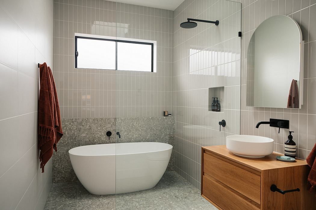 A modern bathroom with a freestanding tub, granite countertop, and wood vanity.