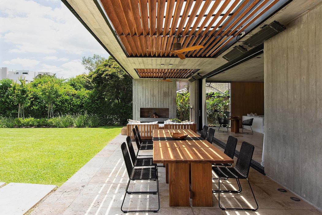 Expansive outdoor living space with wooden beams, lush greenery, and minimalist furnishings.