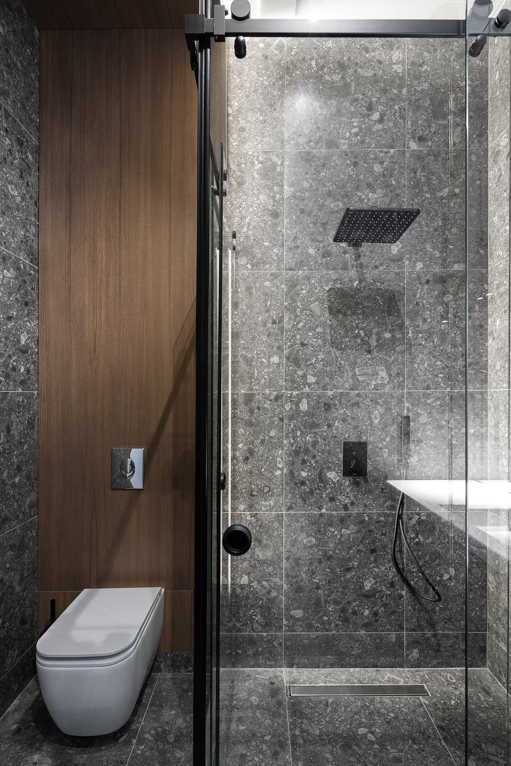 A modern, slate-tiled bathroom with a glass shower enclosure and sleek, minimalist fixtures.