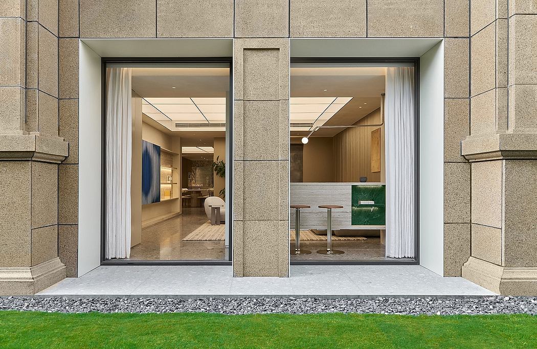 Minimalist architectural facade with textured granite walls and glass entryway revealing modern interior.
