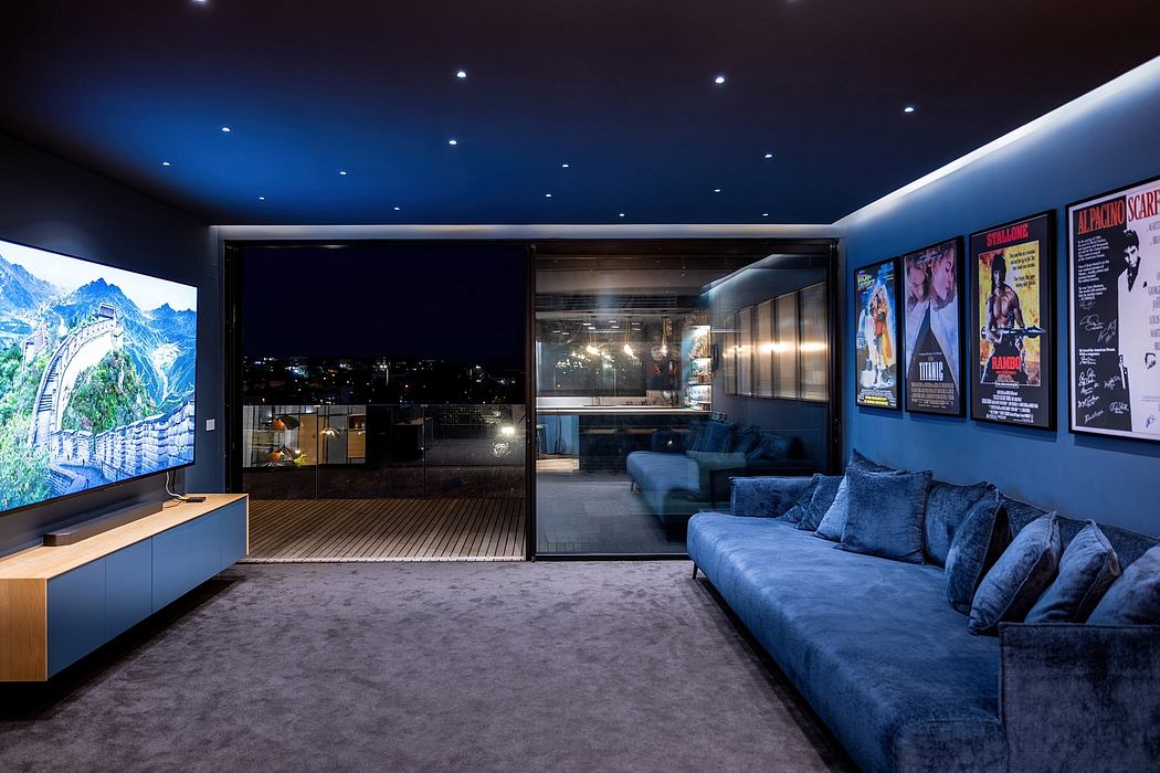 Cozy home cinema with plush blue sofa, wall art, and expansive mountain view through glass doors.