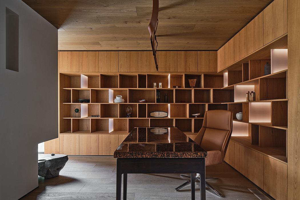 A modern, minimalist workspace with floor-to-ceiling wooden shelves, a luxurious leather chair, and a striking stone desk.