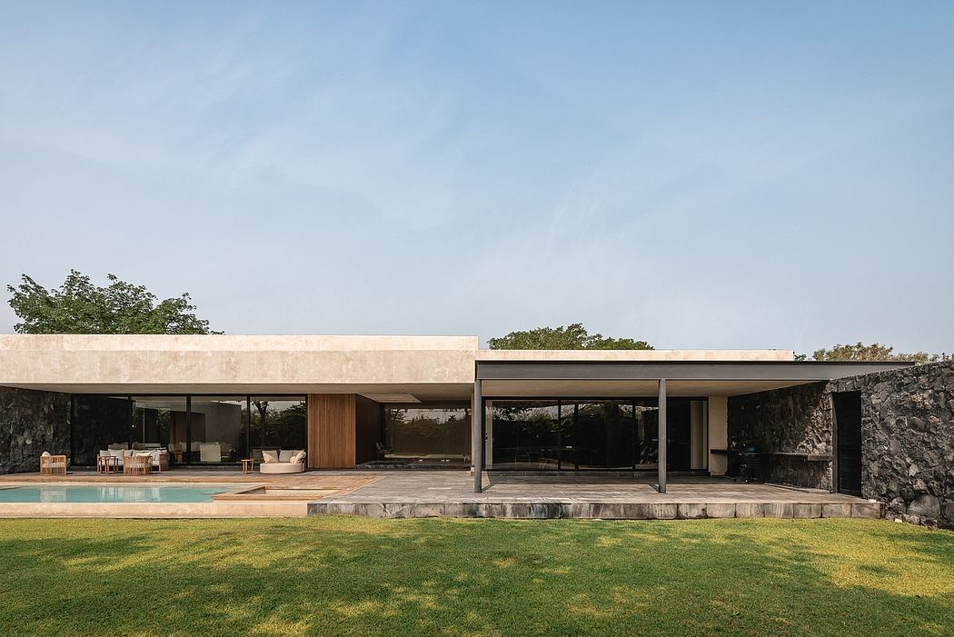 A modern, minimalist house with an open-plan layout, expansive windows, and a pool overlooking a lush lawn.