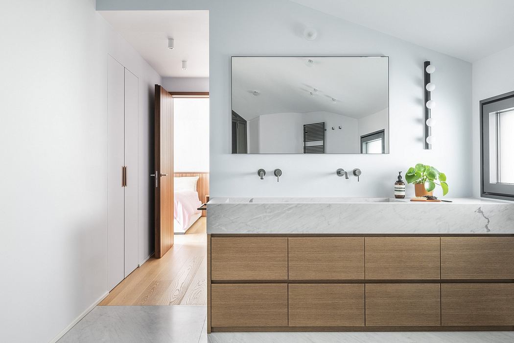 Spacious bathroom with marble countertop, wooden drawers, and modern lighting fixtures.