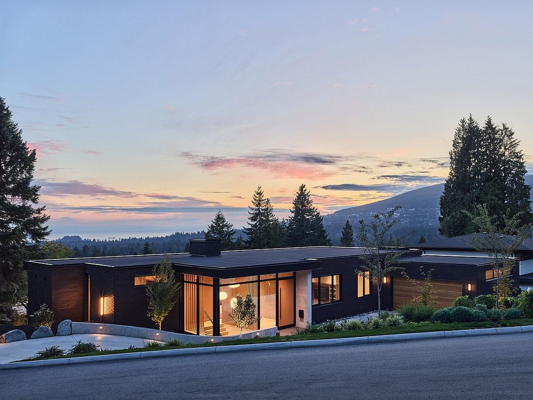 Sleek, contemporary home with warm lighting, surrounded by natural landscape at sunset.