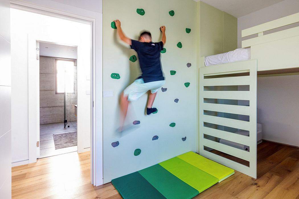 A modern bedroom with a colorful climbing wall and bunk beds, showcasing dynamic interior design.