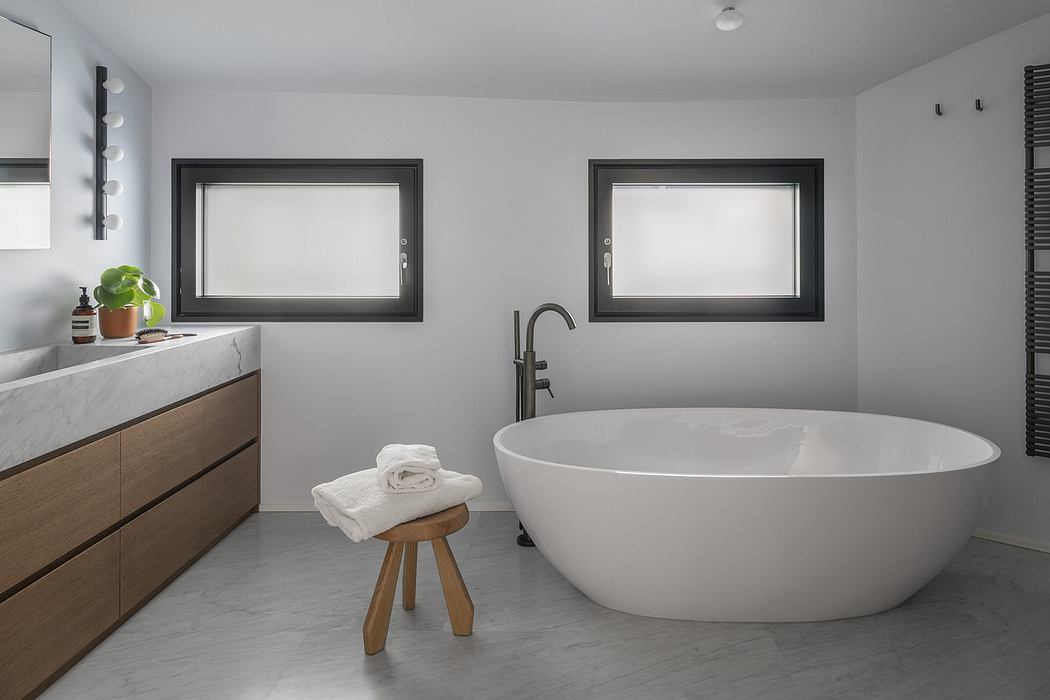 A modern bathroom with a freestanding tub, minimalist vanity, and large windows.