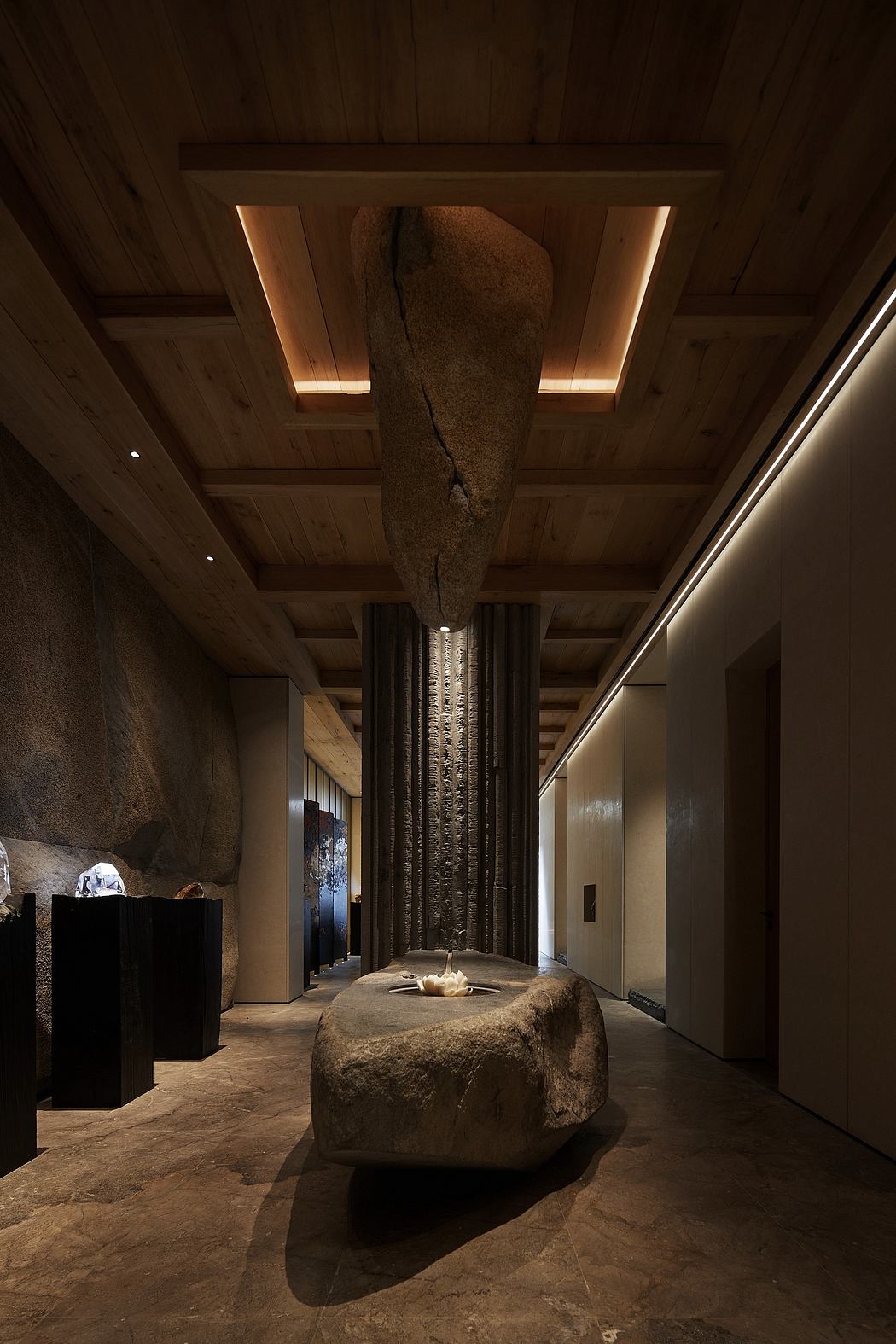 A grand stone hall with dramatic lighting, intricate architectural details, and a massive boulder.