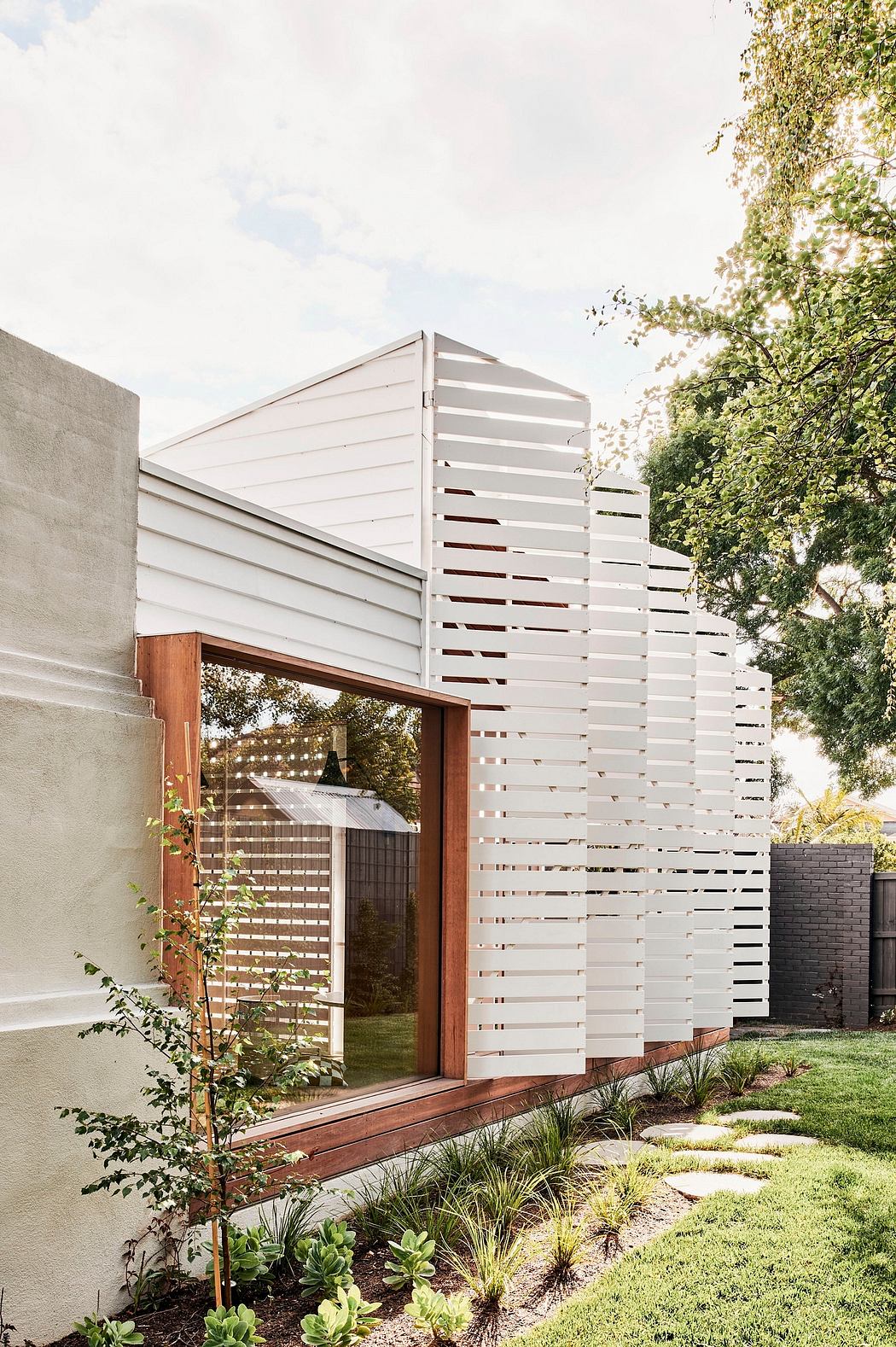 A modern, white-walled structure with a distinctive slatted wooden facade and an inviting outdoor space.