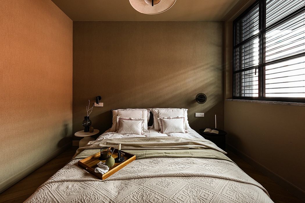 Cozy bedroom with warm lighting, patterned bedding, and a tray of refreshments on the bed.