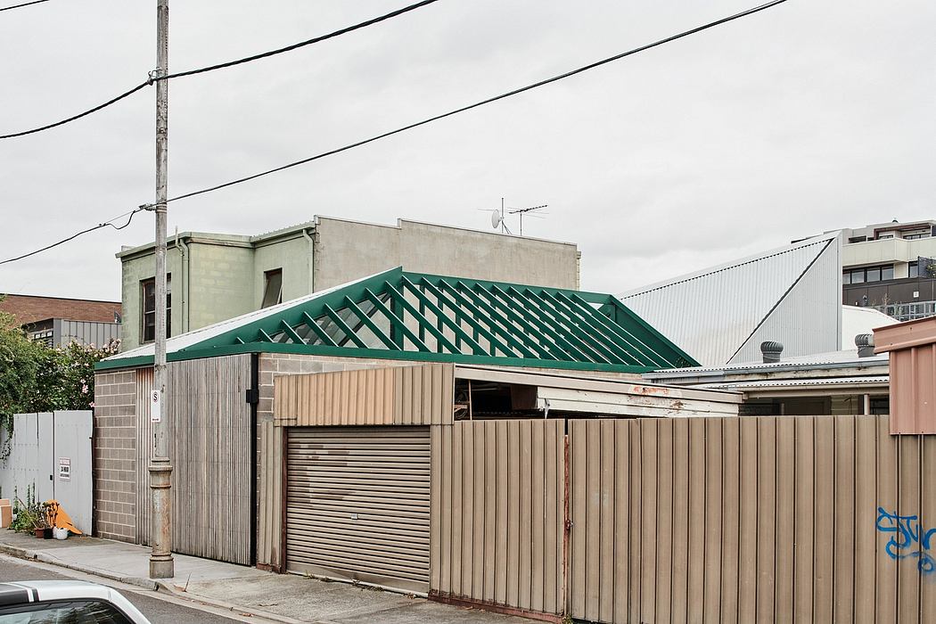 Weathered industrial building with a distinctive green metal roof and roll-up doors.