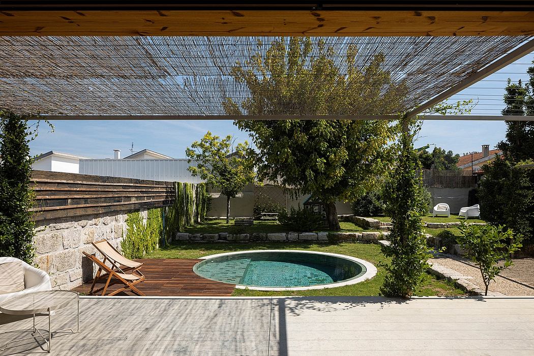 Tranquil backyard oasis with circular pool, patio, and lush vegetation under a thatched roof.