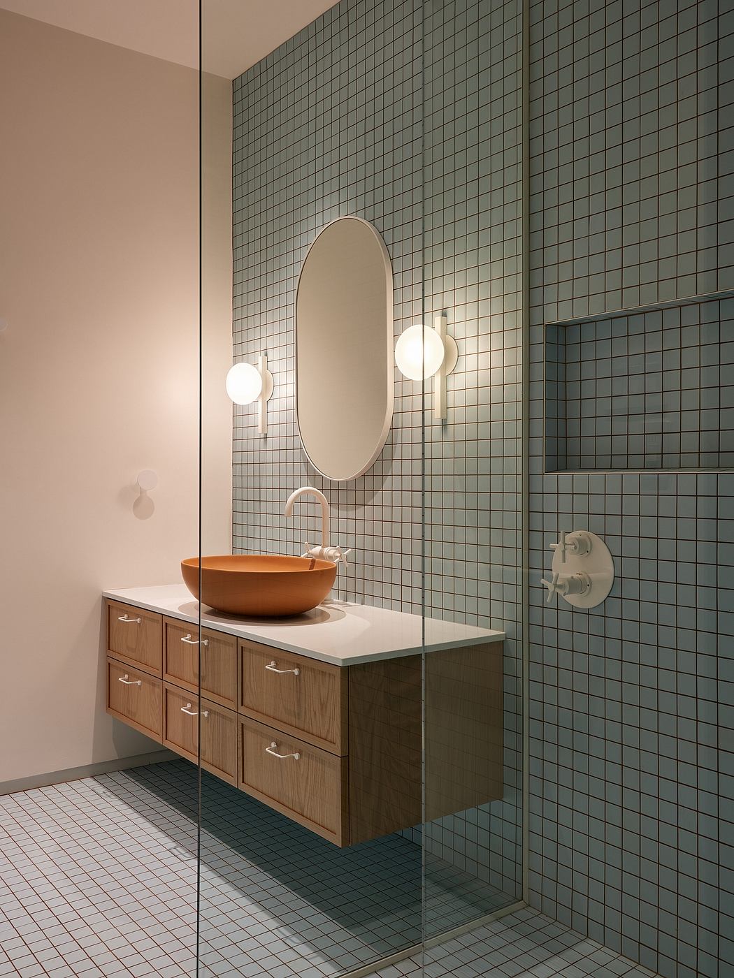 Sleek, modern bathroom with tile walls, wooden vanity, and oval mirror with pendant lighting.