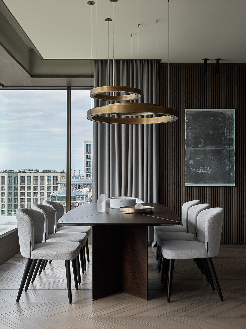 Elegant dining area with modern pendant lights, dark wood table, and plush gray chairs.