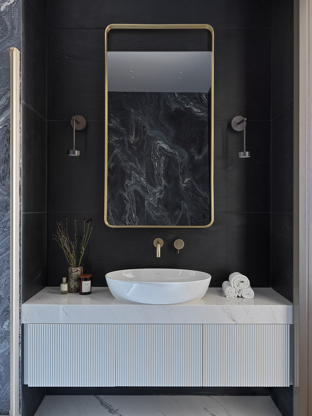 A sleek, modern bathroom with a marble vanity, circular white sink, and a large framed mirror.
