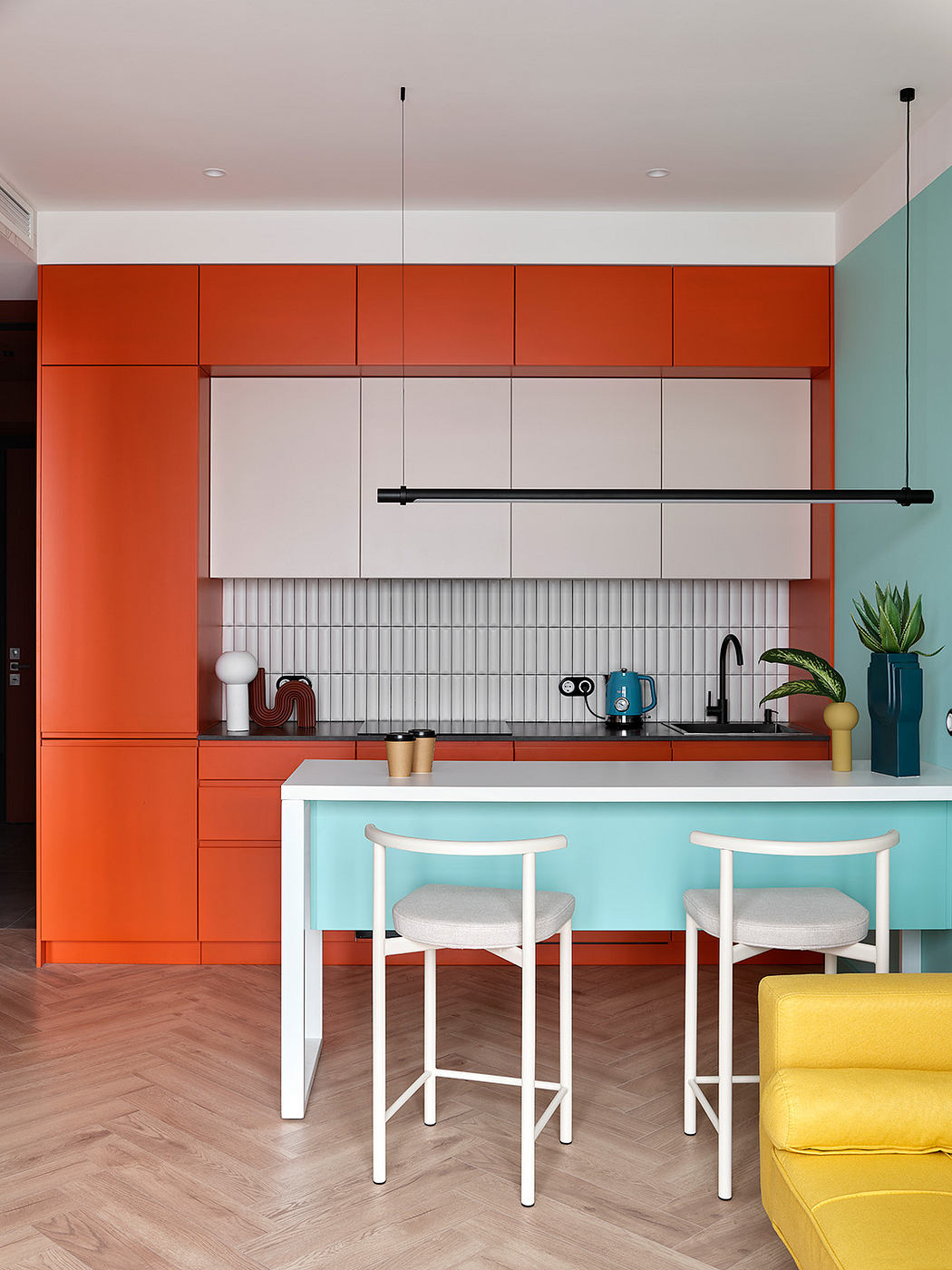 Vibrant orange kitchen cabinetry, white countertops, and a mint green seating area.