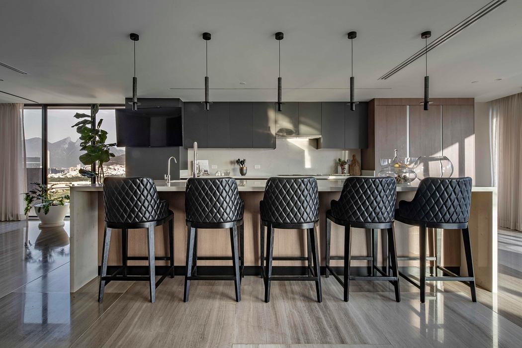 Sleek, modern kitchen with black quilted bar stools, industrial pendant lights, and panoramic view.
