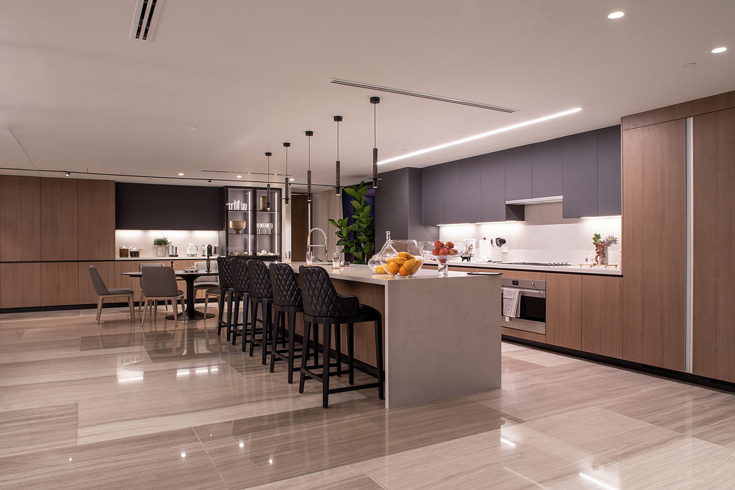 Sleek, modern kitchen with hanging pendant lights, dark cabinetry, and a large center island.