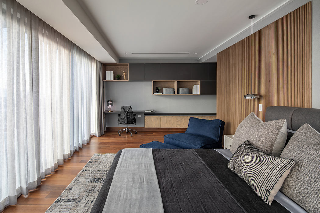 Contemporary bedroom with minimalist wood paneling, built-in shelving, and comfortable seating.