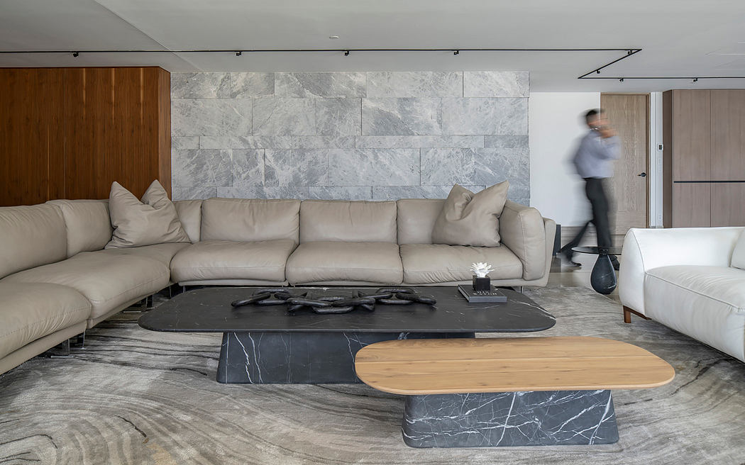 A modern living room with sleek marble walls, a large beige sofa, and a minimalist wooden coffee table.