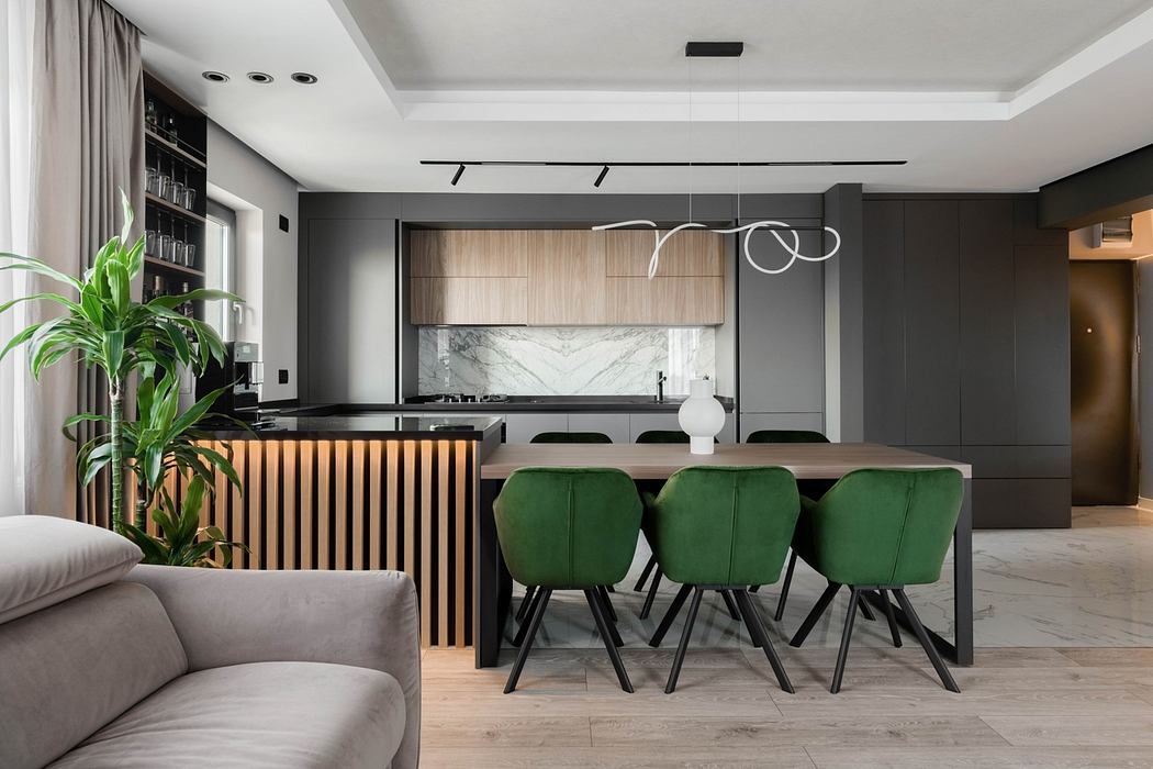 Sleek modern kitchen with dark cabinetry, marble backsplash, and plush green dining chairs.