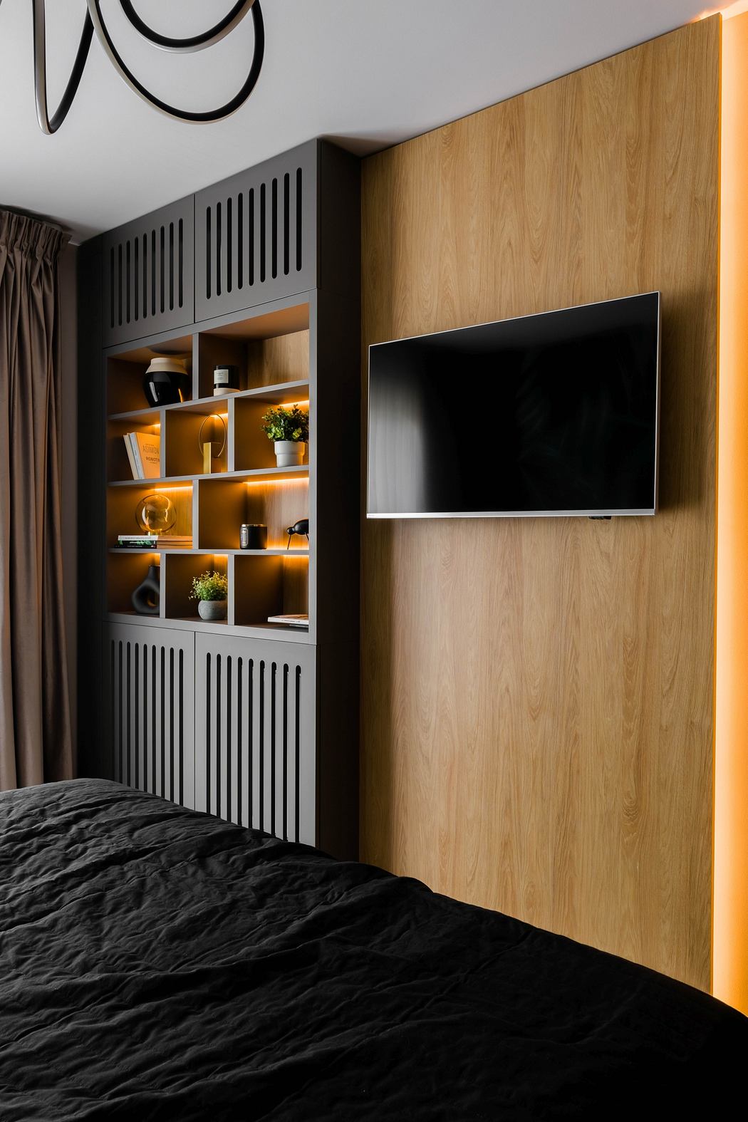Sleek, modern bedroom with wood paneling, built-in cabinets, and mounted TV.