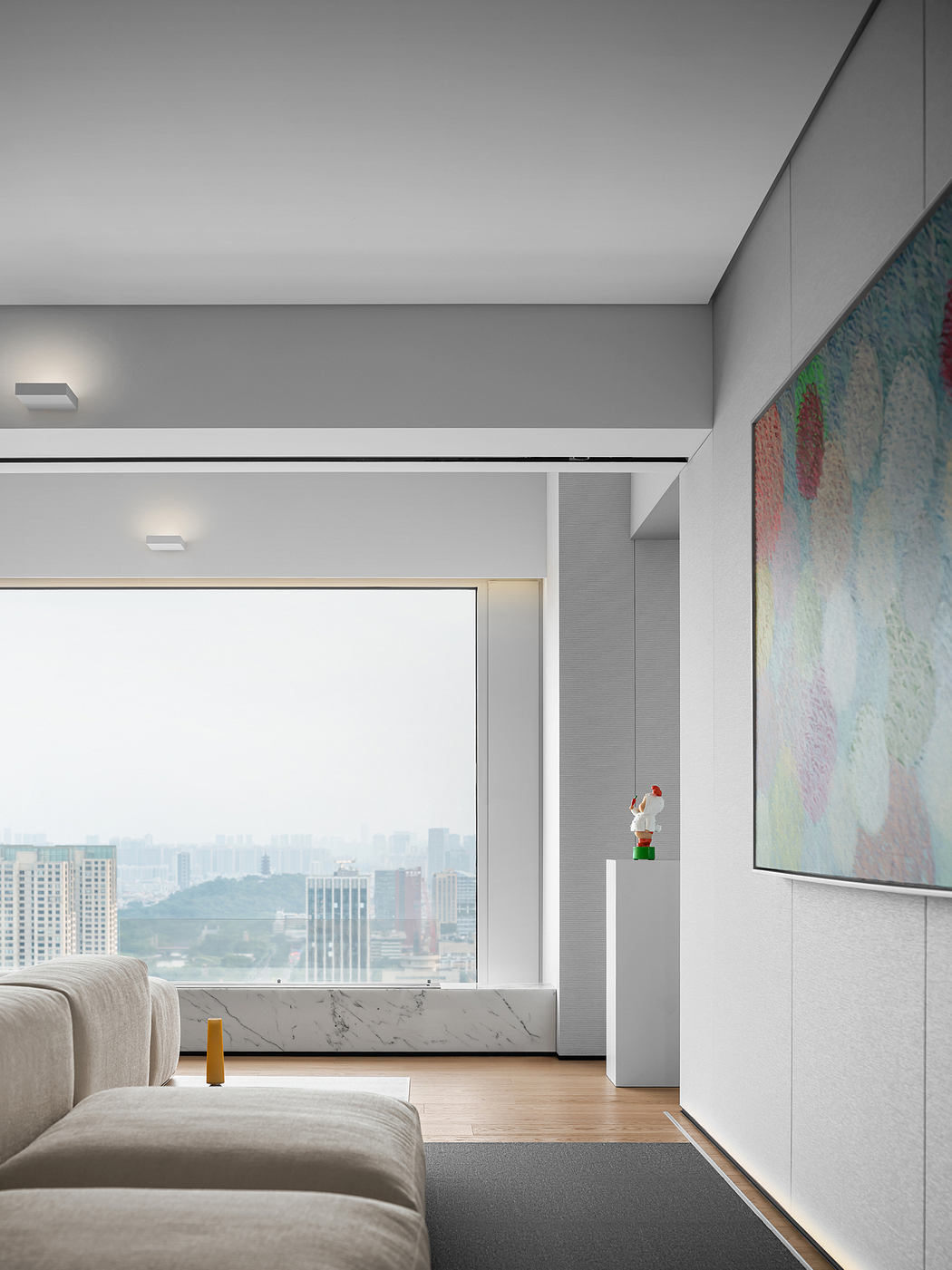 Modern and minimalist living space with a stunning city view through large windows, sleek furnishings, and a vibrant abstract artwork.