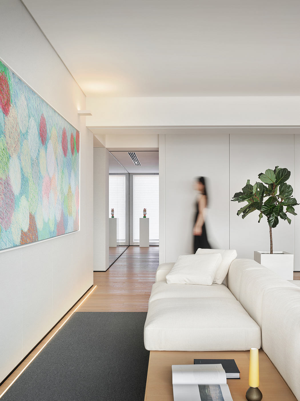 Minimalist living room with vibrant abstract artwork, modern furniture, and potted plant.