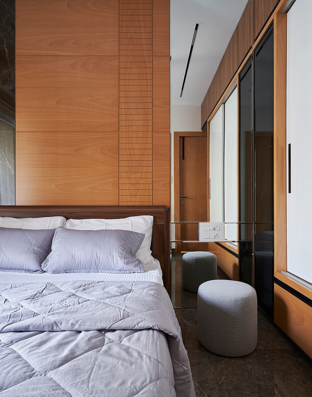 A modern bedroom with warm wood paneling, plush bedding, and minimalist decor.