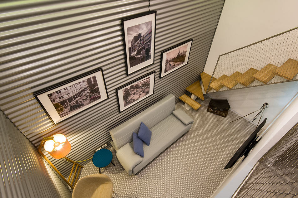 Modern interior with industrial-style corrugated metal walls, vintage photographs, and eclectic furnishings.