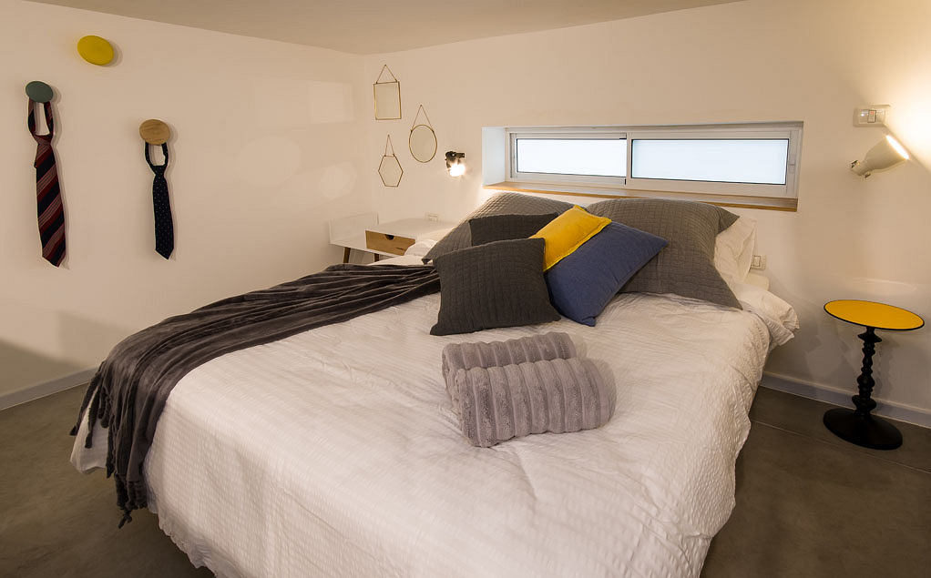 Cozy bedroom with stylish geometric wall decor, plush bedding, and accent lighting.