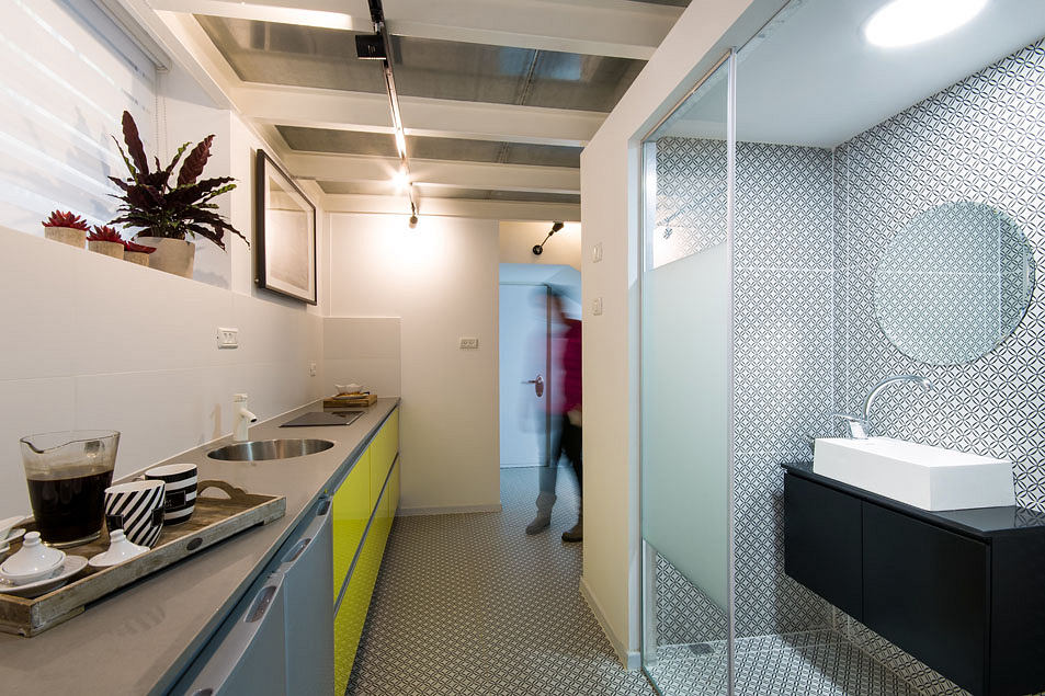 A modern kitchen with sleek cabinets, patterned tiles, and an open bathroom layout.