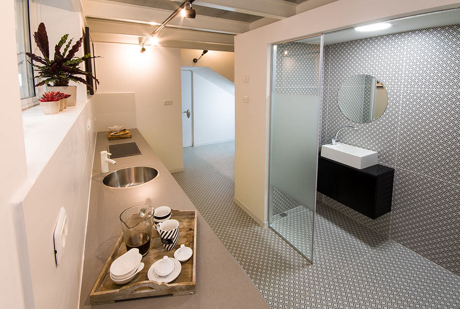 Chic modern kitchenette with sleek basin, patterned tiles, and discreet bathroom.
