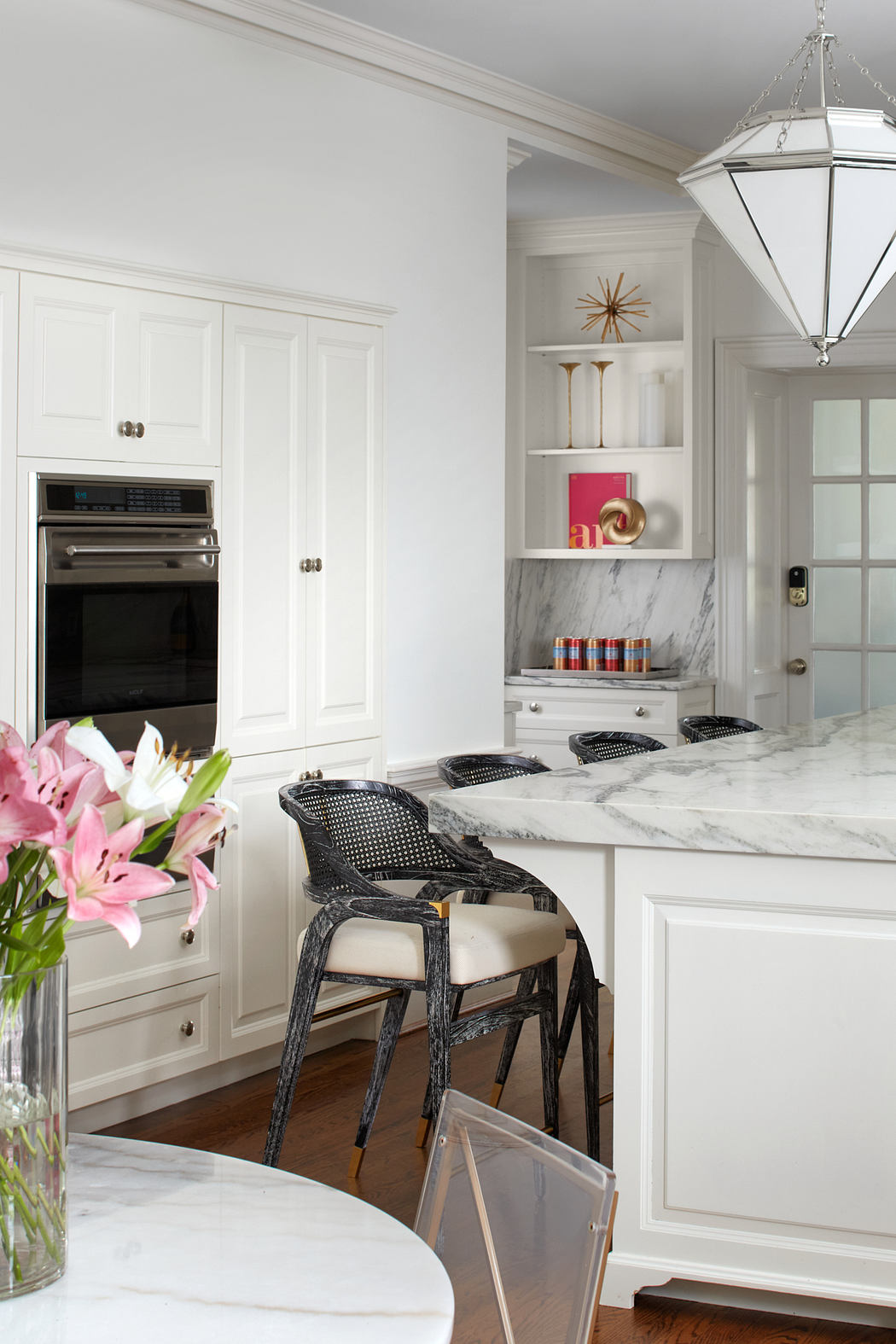 Elegant white kitchen with marble countertops, built-in cabinetry, and stylish lighting.