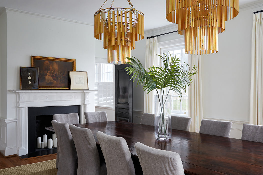 Elegant dining room with ornate golden chandeliers, a fireplace mantel, and potted plants.