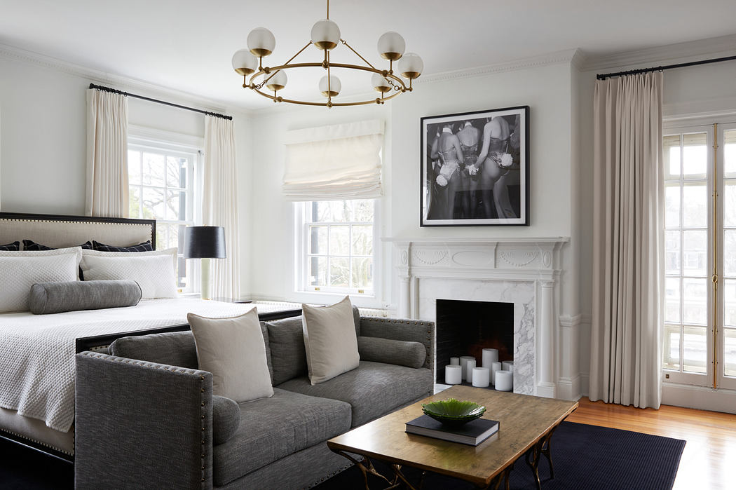 Elegant bedroom with fireplace, large sofa, and an ornate chandelier overhead.