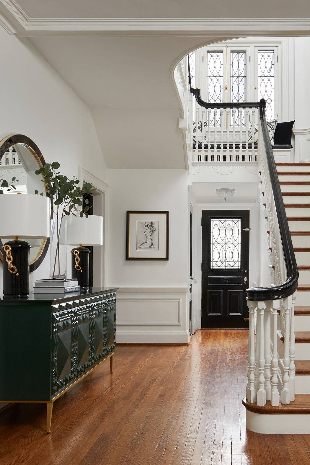 Grand entryway with ornate staircase, leaded glass windows, and elegant furnishings.