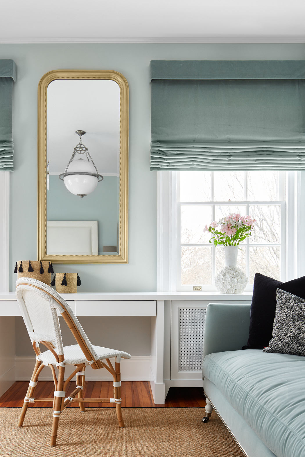 Elegant room with gold-framed mirror, plush seating, and verdant roman shades.