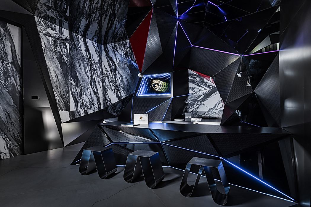 Modern angular architectural space with bold geometric shapes, lighting, and Lamborghini branding.