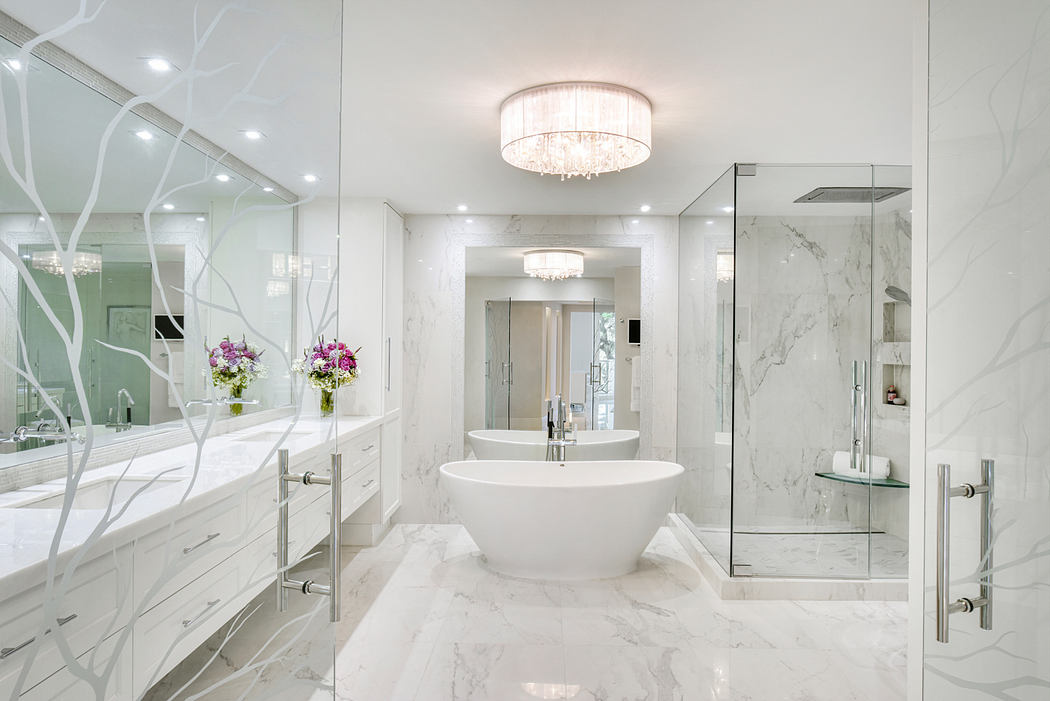 Elegant marble bathroom with freestanding tub, crystal chandelier, and glass shower enclosure.