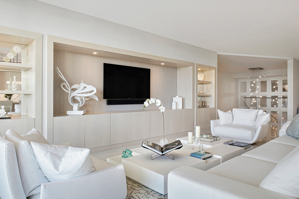Elegant modern living room with minimalist decor, open shelving, and a large TV mounted on the wall.