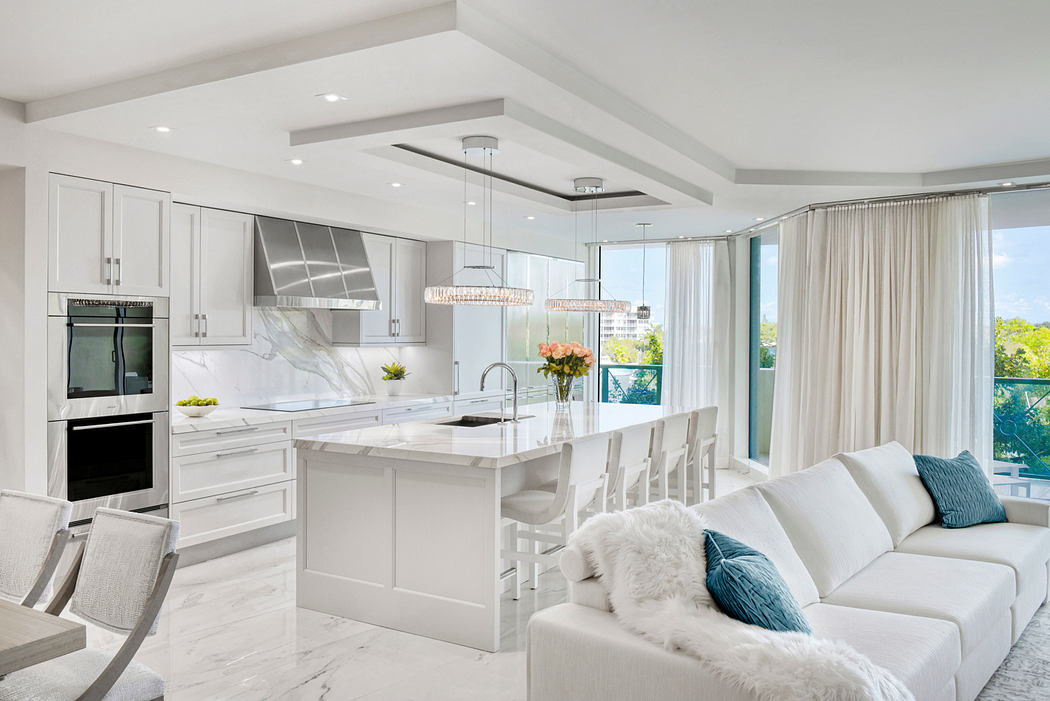Open-concept kitchen with marble countertops, pendant lighting, and adjacent lounge area.