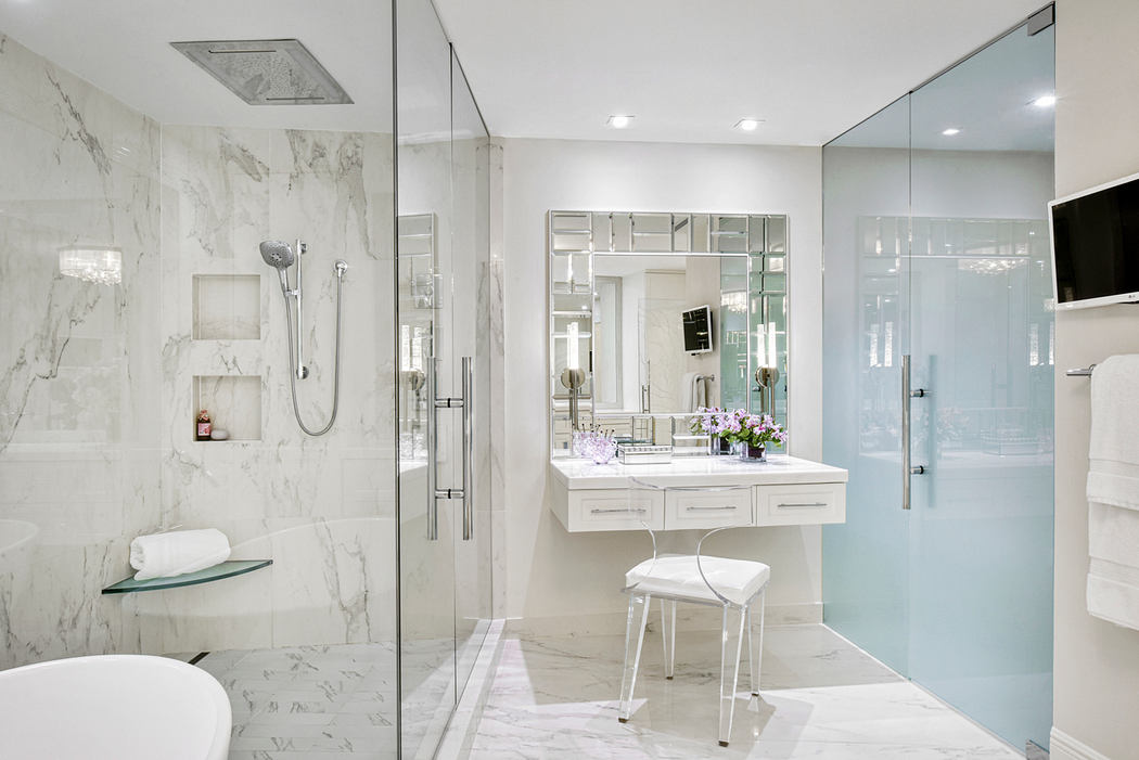 A sleek, modern bathroom with a marble-tiled shower, vanity, and glass enclosure.
